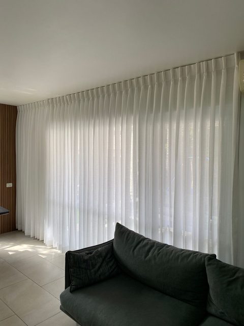 סלון — וילון פשתן שקוף לאורך קיר החלונות כולו